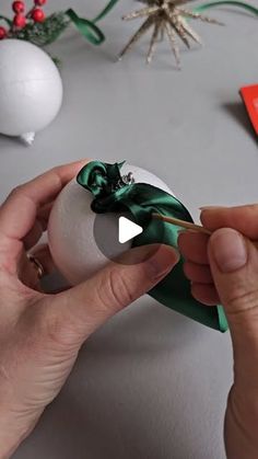 someone is decorating an ornament with green ribbon