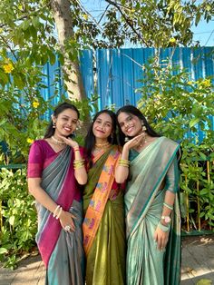 three women standing next to each other wearing sari and holding their arms around one another