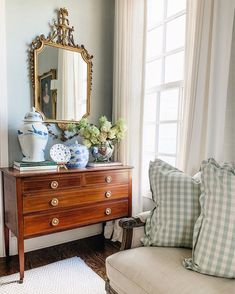 a living room scene with focus on the dresser and mirror in the corner that is next to the couch