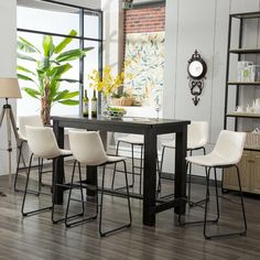 a dining room table with four chairs and a clock on the wall in front of it