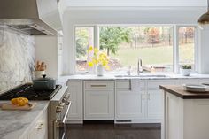 a kitchen with marble counter tops and white cabinets, along with an island in the middle