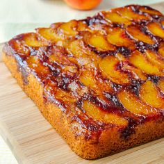 a close up of a piece of bread on a cutting board with fruit in the background