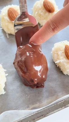 someone is dipping almonds on top of chocolate