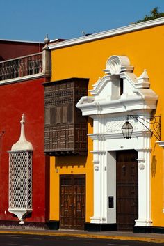 an old building painted yellow, red and white with wooden doors on the outside wall