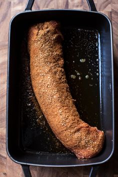 a cooked sausage in a black pan on a wooden table