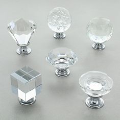 an assortment of crystal knobs and pulls on a gray surface with white background,