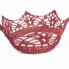 a red crocheted lace bowl on a white tablecloth with an intricate design