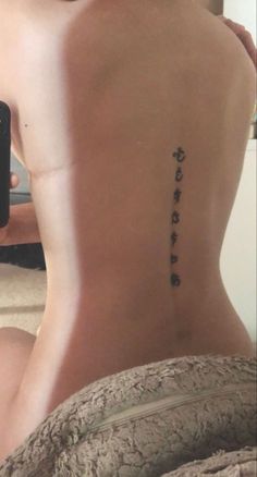 the back of a woman's lower back tattoo with words written in cursive writing