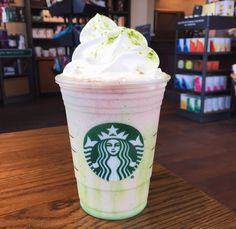 a starbucks drink with whipped cream and green sprinkles on the top is sitting on a table