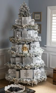 a christmas tree made out of boxes and wrapped in white paper with presents on top