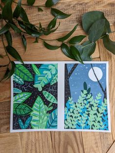 two cards with green leaves and blue sky in the background on a wooden table next to a potted plant