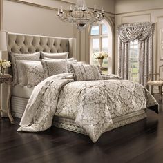 a bedroom with a bed, chandelier and window in the background on a hard wood floor