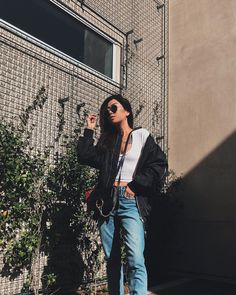 a woman standing in front of a building with her hand on her hip while wearing sunglasses