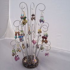 a vase filled with lots of different types of earrings on top of a white table