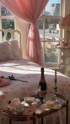 a bottle of champagne on a tray in front of a bed with pink drapes