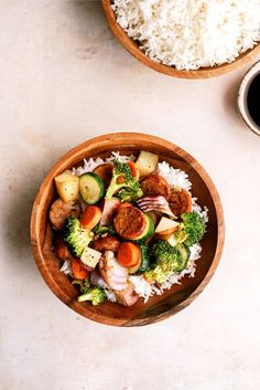 two bowls filled with rice, meat and veggies next to a cup of coffee