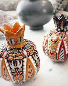 two decorative vases sitting on top of a white table next to each other,