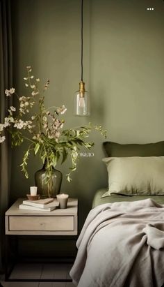 a bedroom with green walls and white flowers in a vase on the nightstand next to the bed