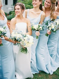 a group of women standing next to each other holding bouquets in their hands and smiling