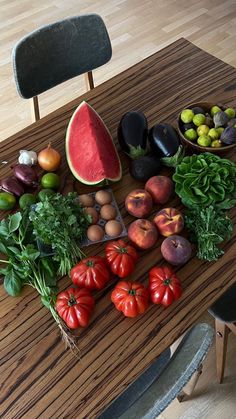 a wooden table topped with lots of different types of fruits and vegetables on top of it