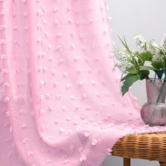 a vase filled with flowers next to a pink curtain