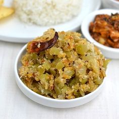 three bowls filled with food sitting on top of a white table covered in rice and other foods