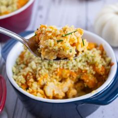 a spoon full of food sitting in a blue bowl on top of a white table