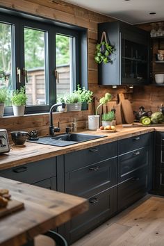 a kitchen filled with lots of wooden counter tops and black cabinets next to a window