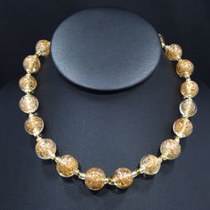 *Description: This is a beautiful clear Murano Italian glass beaded necklace made in the 1930s and filled with flecks of copper & gold which looks like glitter. Gold and copper within the beads is referred to as Aventurine. The necklace was designed with 20 12mm beads separated by clear and gold seed beads. There are six 8mm beads which are wire wrapped to add a matching extension chain. These are gorgeous Venetian beads and as a bead collector, these are one of my favorites. It is a beautif Vintage Gold Polished Beads, Vintage Polished Gold Beads, Antique Gold Necklace With Large Beads, Vintage Clear Round Bead Necklaces, Antique Gold Jewelry With Spacer Beads, Vintage Handmade Clear Necklace, Gold Czech Glass Single Strand Jewelry, Vintage Amber Glass Necklaces, Clear Glass Round Bead Necklaces