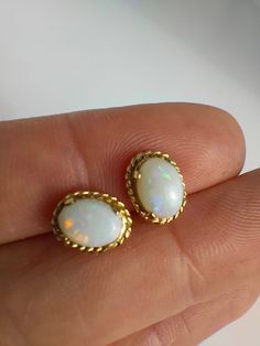 Opals are a very popular gem stone and looking at these earrings it's clear to see why! Each of these opals have a wide range of colours that glow as they hit the light, a bit like iridescent confetti - magical little stones! The opals are oval shaped cabochons set in 9ct yellow gold. Perfect condition Fully hallmarked on the earring posts for 9ct gold The front of each earring measures 1cm x 0.7cm across. Classic Oval Opal Jewelry, Formal Oval Opal Earrings, Oval Opal Earrings For Formal Occasions, Oval Opal Jewelry With Matching Earrings, Vintage White Oval Earrings, Gold Opal Cabochon Earrings, Yellow Gold Oval Opal Earrings, Oval Opal Earrings In Yellow Gold, Earrings Studs