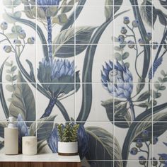 a tiled wall with blue flowers on it and two white vases next to it