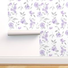 the wall paper has purple flowers on it and is next to a roll of toilet paper