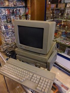 an old computer sitting on top of a desk in a room filled with books and magazines