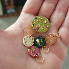 a person is holding five different colored keychains in their hand, one with sprinkles on it