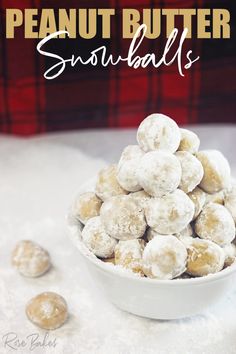 a white bowl filled with snowballs sitting on top of a table next to a pile of cookies