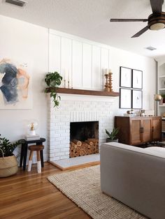 a living room filled with furniture and a fire place in front of a white brick fireplace