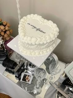 a white cake sitting on top of a table next to pictures and other items in front of it