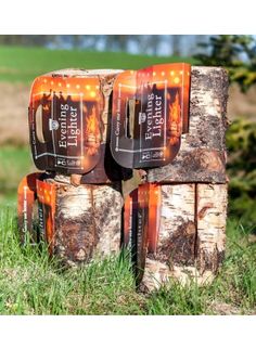 four beer cans stacked on top of each other in the grass next to a tree stump