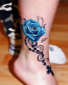 a blue rose tattoo on the foot with rosarys and beads around it, as well as a cross