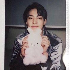 a young man holding a stuffed animal in his right hand and posing for the camera