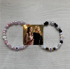 two women are standing next to each other on a white surface with beads and charms