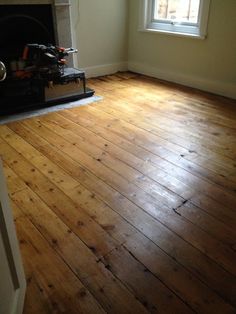 an empty room with wood floors and a fire place