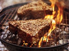 a piece of meat cooking on top of a grill next to some charcoal coals