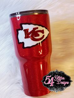 a red tumbler cup with the kansas chiefs logo on it sitting on a white fur background