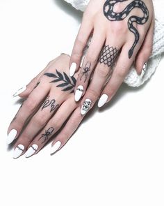 two hands with white and black nail polishes on them, one holding a snake