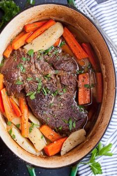 pot roast with carrots, potatoes and parsley in a bowl on a table