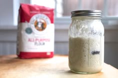 a glass jar filled with liquid sitting on top of a table next to a bag of coffee