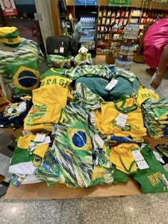 a pile of shirts sitting on top of a wooden table in a store next to other items