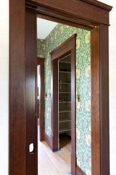 an open door leading into a room with wallpaper on the walls and wooden floors