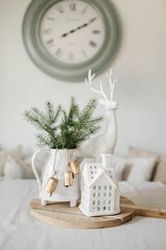 a white deer figurine sitting on top of a table next to a clock